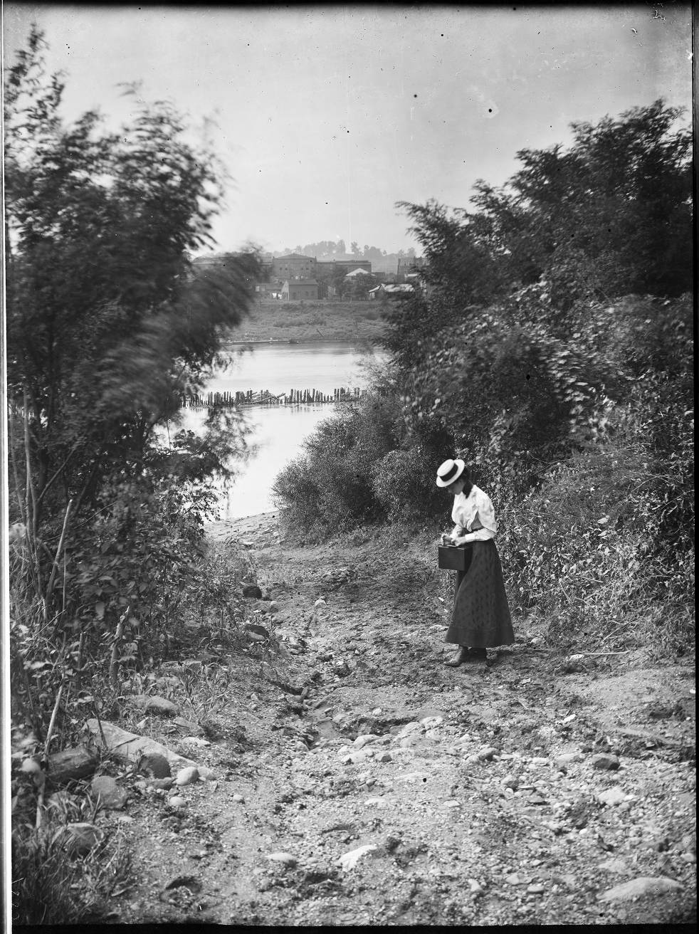 Original black-and-white riverbank scene with a woman carrying a case